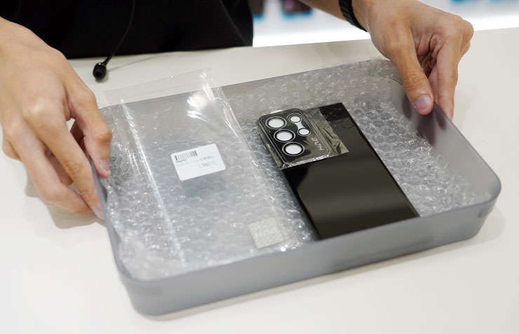 一切準備妥當，店員會將手機與保護貼置放於盒內，準備遞交給無塵包膜室的師傅。