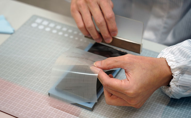 接下來師傅先在機身正面貼上膠膜，作為防止果凍膠溢入手機孔洞的阻隔層。