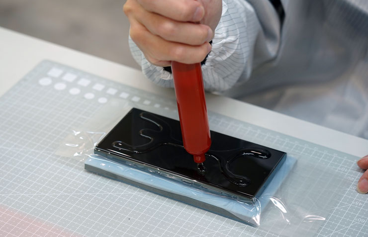 接下來在螢幕上擠上果凍膠，相較於一般的 UV 膠，小豪包膜的果凍膠配方較沒有這麼濃稠，因此師傅擠出的果凍膠量不少，以便等一兒玻璃貼的緊密貼合。