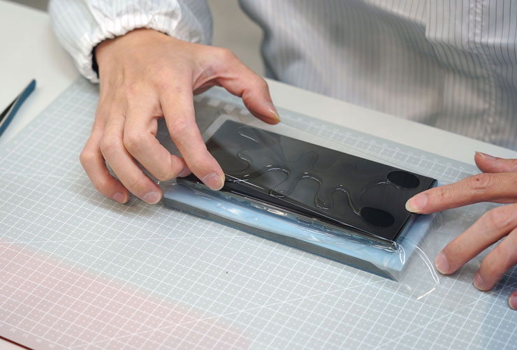 玻璃保護貼登場，師傅小心覆蓋在果凍膠上。
