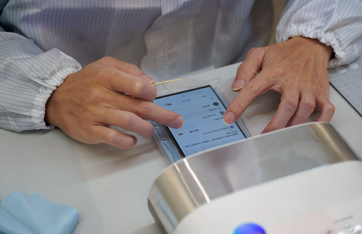 師傅用手指確認果凍膠是否平均，這個程序非常考驗師傅的經驗，確認之後即可進入 UV 紫外燈機照射讓果凍膠固化。