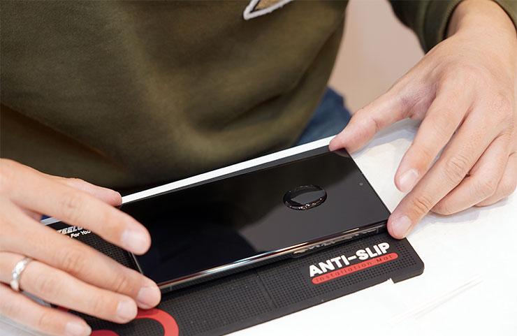 在螢幕擠上 UV 膠，用量約一顆 10 元硬幣大小，並輕搖機身調整 UV 膠位置。