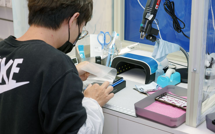 相較於無塵包膜室需要全身著裝防塵衣，使用無塵桌時師傅只需要著防塵袖套即可，相對更節省準備時間。