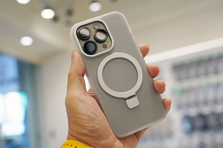「磁吸立架手機殼」安裝至 iPhone 15 Pro 的背面，搭配白色的金屬鏡頭框、Magsafe 磁吸環也相當好看。