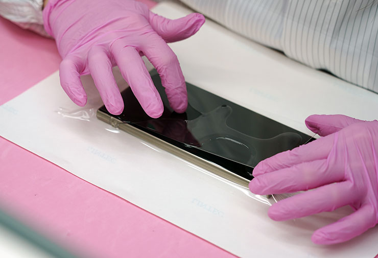 在果凍膠液化狀態下，覆蓋上玻璃貼，進行對位與氣泡擠壓，由於 HAO 5D 果凍膠玻璃保護貼是全透明設計，因此會需要師傅精準拿捏手機四邊等距，才能在邊緣保留適當的退縮空間，以符合裝上保護殼使用的需求。