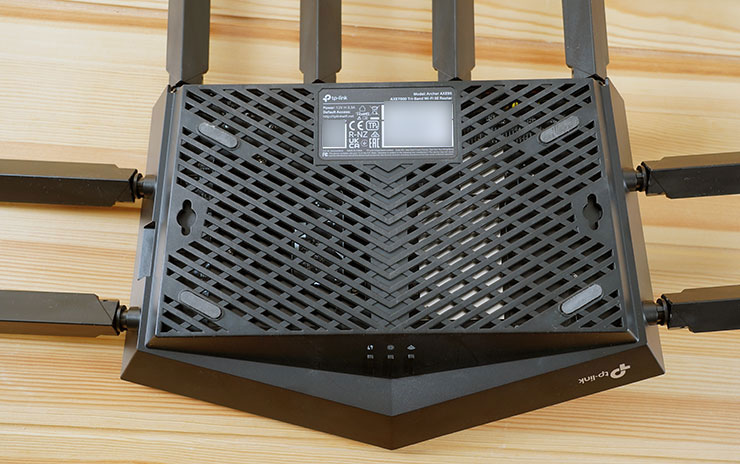 機身底部可以看到大面積的散熱孔，確保機身內的熱氣可以順暢排出，靠近頂部的標籤也標示了預設 SSID 與密碼，在安裝初始設定時會需要使用到。