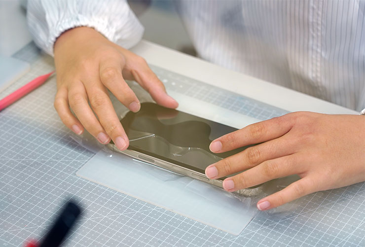 接下來覆蓋上玻璃保護貼本體，等待空氣排出，在無塵包膜室安裝的好處，就是可以避免保護貼黏合時會有灰塵卡在其中，造成氣泡產生，那可就前功盡棄了！