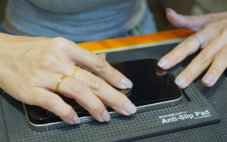 清潔完成後，將保護貼由聽筒這一側對準位置後放下，老闆娘有提到，因為佳佳貼 JiaPlus 的尺寸完全考量了 iPhone 16 系列的尺寸，尤其 Pro 系列今年的邊框更窄，因此在對位時要避開聽筒的細縫，才不會影響聽講電話時的音量。